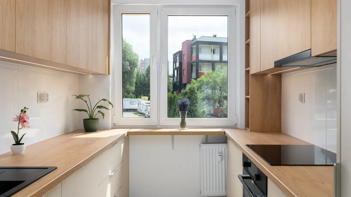 Galley Kitchen Layout Guide: How to Make a Narrow Kitchen Work Wood-finish galley kitchen with window at the end