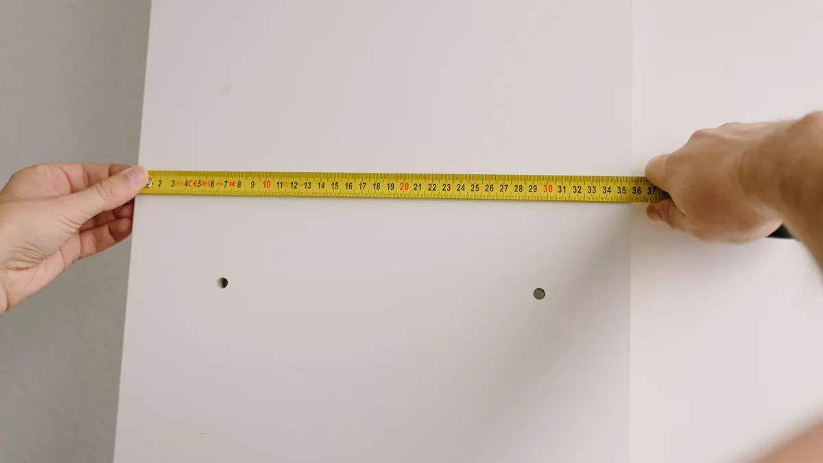 Kitchen Dining Furniture Guide: How to Choose Pieces That Fit the Room Hands measuring a wall with a tape measure
